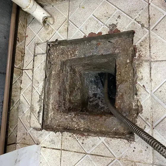 Cabo da máquina rotativa desobstruindo caixa de esgoto