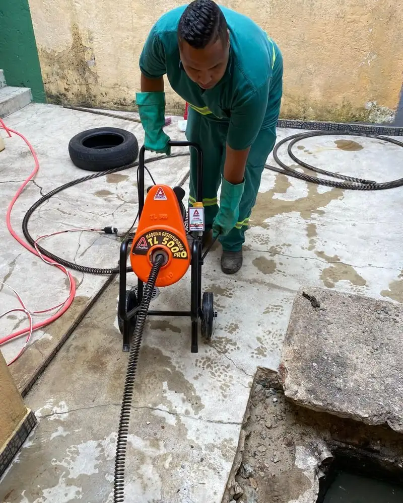 Profissional da FS Desentupimento operando máquina de desentupimento rotativa